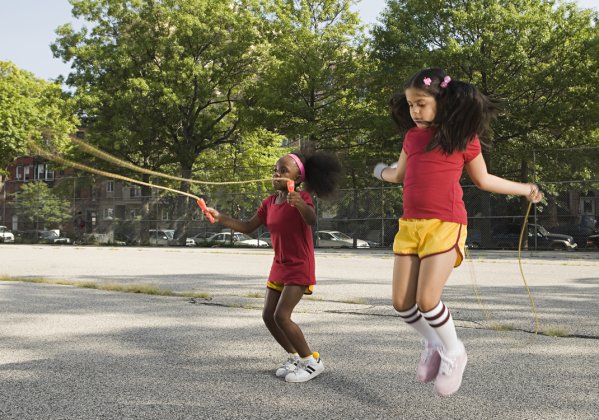 Two kids jumping rope on a blacktop playground