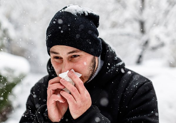 Man blowing his nose in the snow